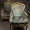 Pair of French Louis XV style bergére chairs with hand carved frame and wood pegged construction