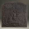 Late 17th century Flemish cast iron fireback with a cupid holding a torch standing in foliage.