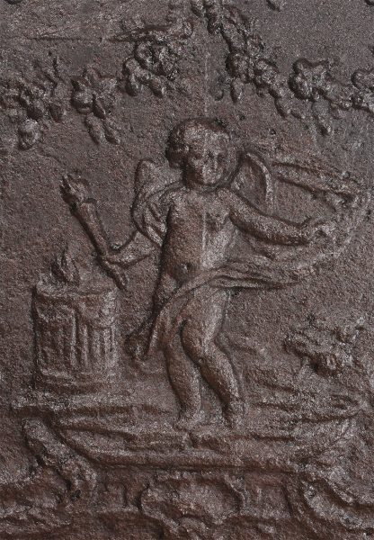 Late 17th century Flemish cast iron fireback with a cupid holding a torch standing in foliage.