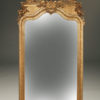 Ornate French beveled mirror with gilded frame depicting cherubs, birds and urn