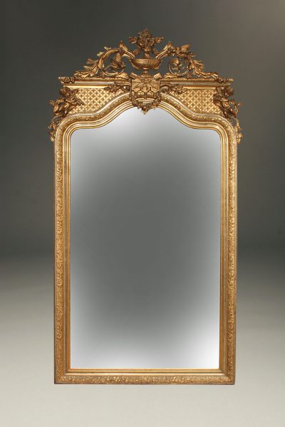 Ornate French beveled mirror with gilded frame depicting cherubs, birds and urn